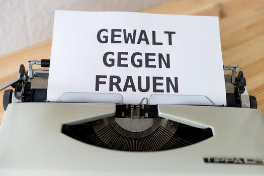 Schreibmaschine mit wei&szlig;em Papier, auf dem in Gro&szlig;buchstaben "GEWALT GEGEN FRAUEN" geschrieben steht