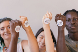 Verschiedene Frauen halte Sticker in die Kamera mit der Aufschrift "Vote"