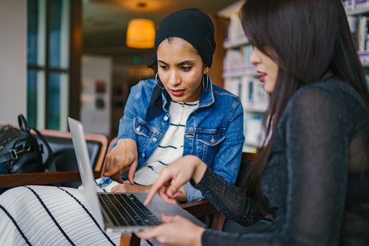 zwei Frauen schauen gemeinsam auf einen Laptop